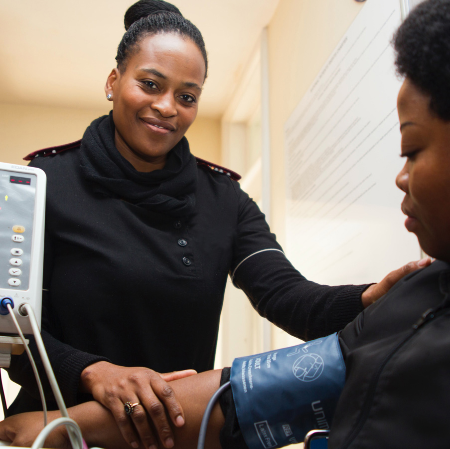 Medical Assistant smiling as she takes a patient's blood pressure