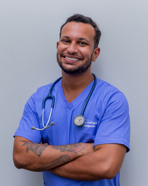 A clinical medical assistant smiles for the camera with his arms crossed